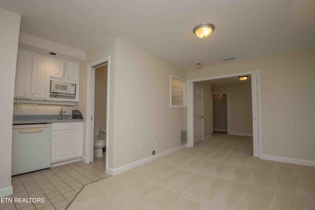kitchen with a sink, white appliances, white cabinetry, baseboards, and visible vents