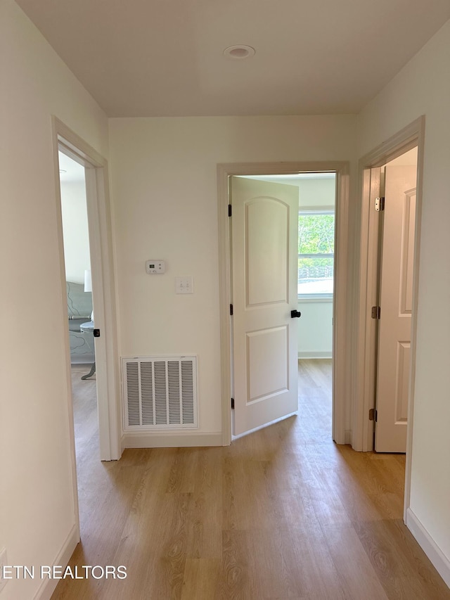 hall featuring visible vents, wood finished floors, and baseboards