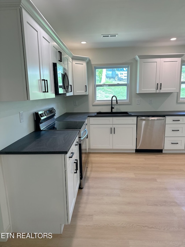 kitchen with plenty of natural light, visible vents, a sink, dark countertops, and appliances with stainless steel finishes