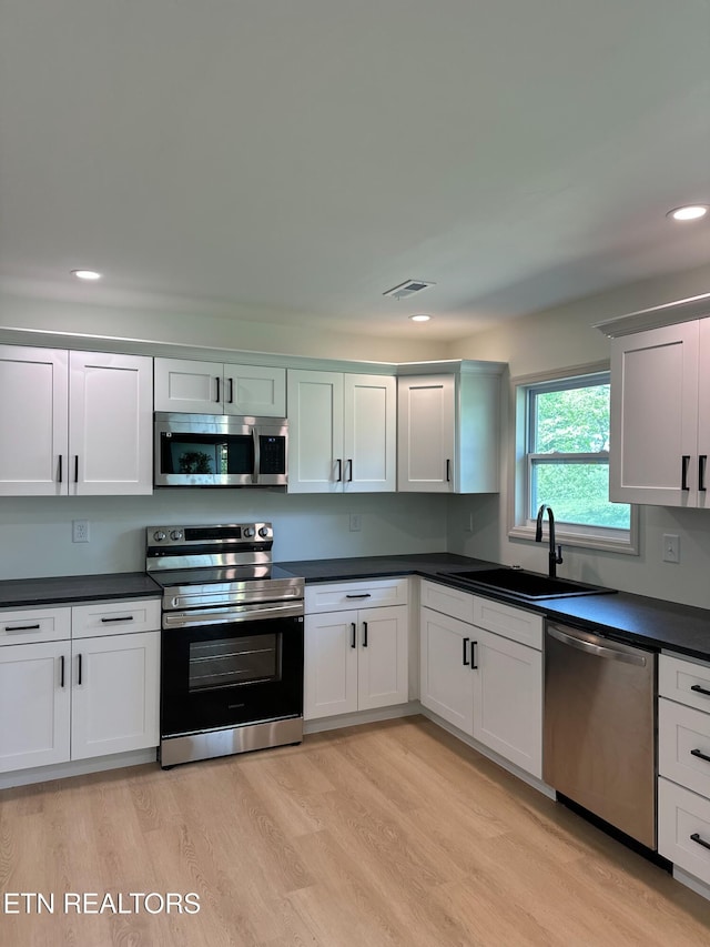 kitchen with dark countertops, stainless steel appliances, visible vents, and a sink
