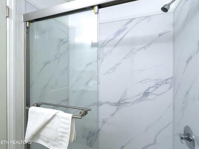 bathroom featuring a marble finish shower