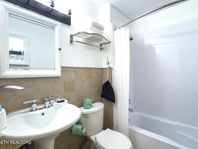 bathroom with toilet, tile walls, shower / tub combo, and a sink