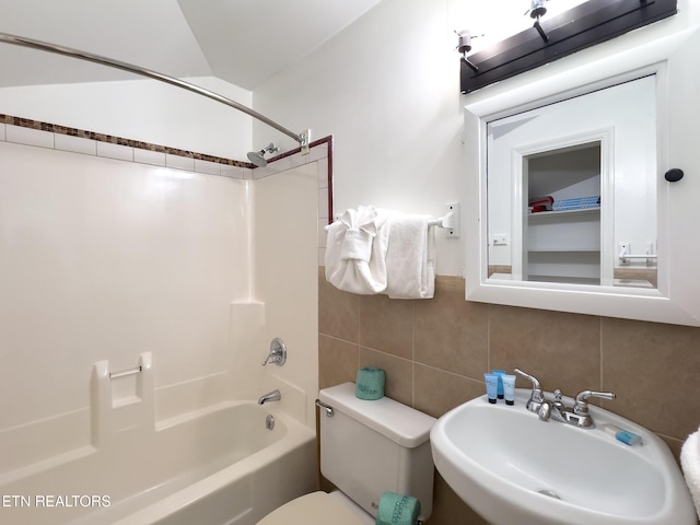 full bath featuring a sink, tile walls, toilet, decorative backsplash, and bathing tub / shower combination