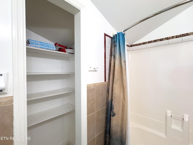 bathroom featuring a shower with shower curtain and lofted ceiling