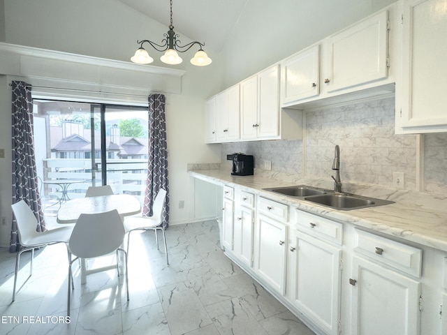 kitchen featuring tasteful backsplash, marble finish floor, a sink, a chandelier, and white cabinets
