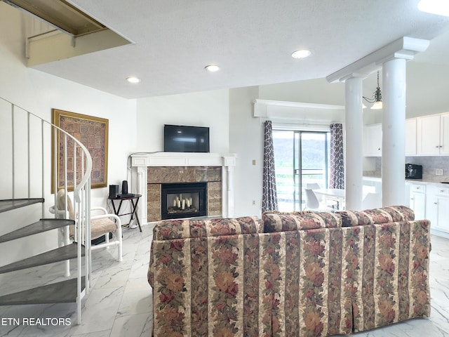 living room with marble finish floor, decorative columns, a fireplace, and recessed lighting