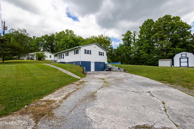172 W Hills Rd, Rutledge, TN 37861 - view of side of property featuring a storage unit, asphalt driveway, a garage, an outbuilding, and a lawn
