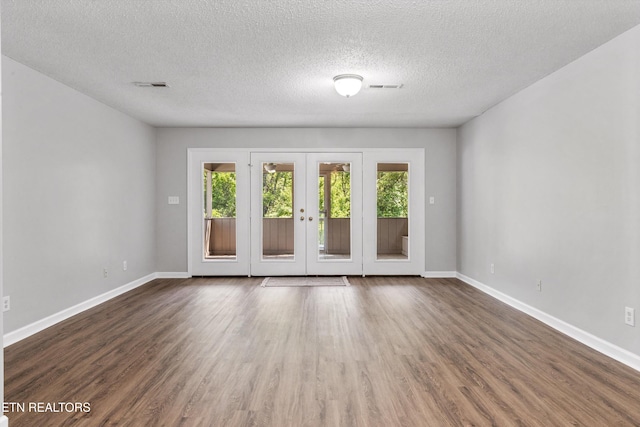 spare room with french doors, wood finished floors, a healthy amount of sunlight, and visible vents