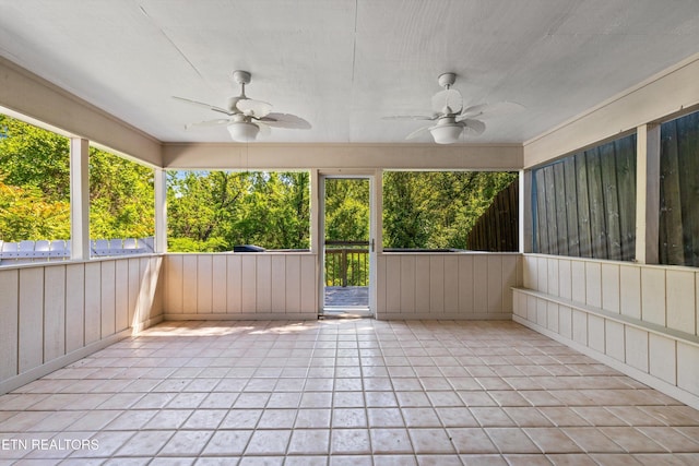unfurnished sunroom with a ceiling fan and a wealth of natural light