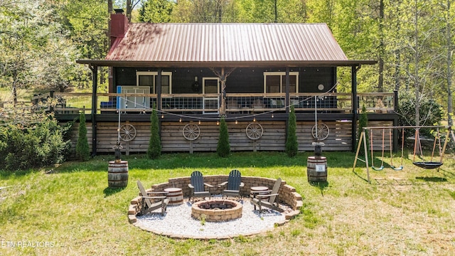 rear view of house featuring a lawn, a fire pit, metal roof, and a chimney