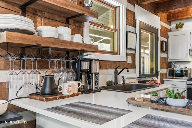 kitchen with a sink, stainless steel microwave, and tasteful backsplash