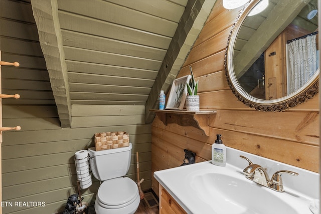bathroom with vanity, wooden walls, and toilet