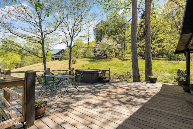 wooden terrace with a lawn, outdoor dining space, and a hot tub