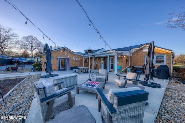 rear view of house with an outdoor living space with a fire pit, a patio area, and brick siding