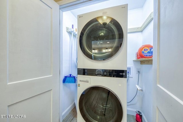 clothes washing area with laundry area, stacked washer and dryer, and baseboards