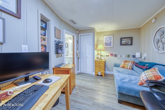 living area with crown molding, light wood-style floors, and visible vents