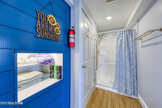 bathroom with baseboards, a shower stall, and wood finished floors