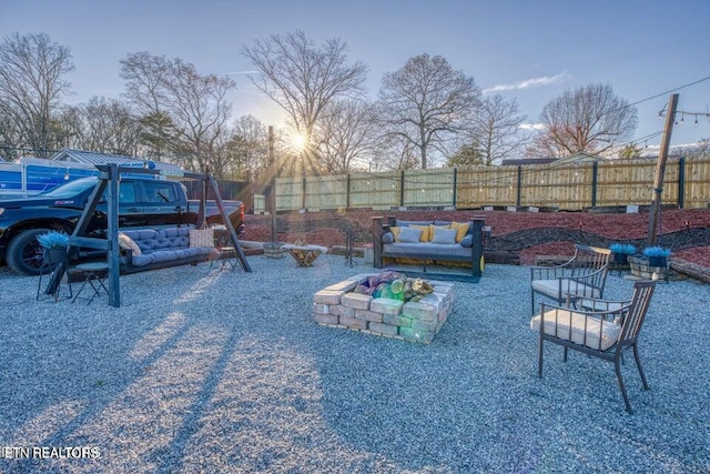 yard at dusk featuring fence and an outdoor living space with a fire pit