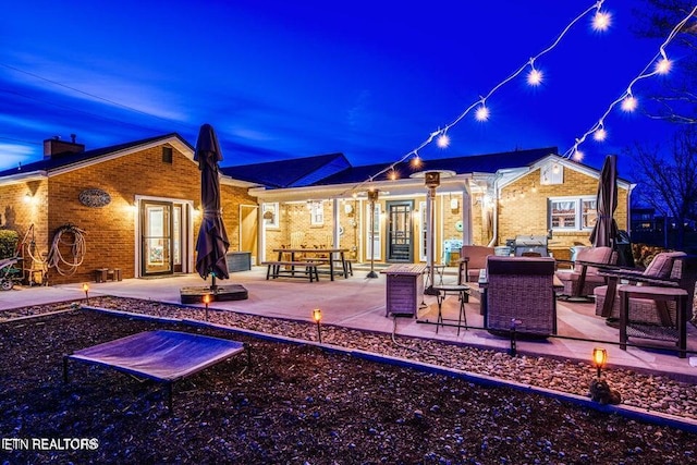 patio at night with an outdoor living space with a fire pit