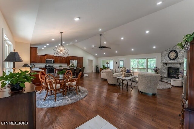 dining room with a ceiling fan, recessed lighting, a stone fireplace, and dark wood-type flooring
