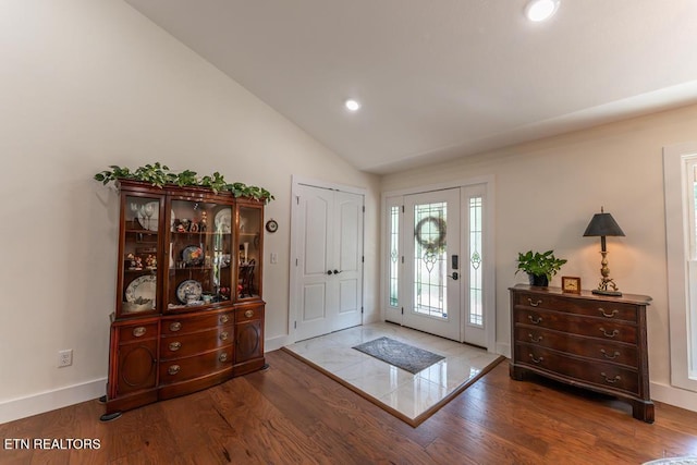foyer with baseboards, wood finished floors, and lofted ceiling