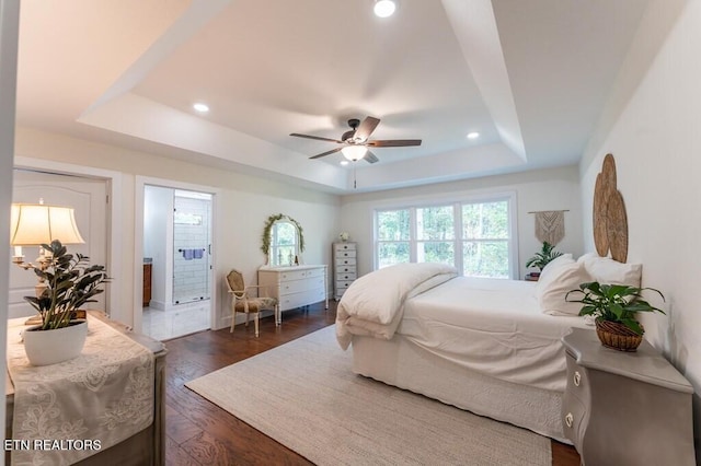 bedroom featuring connected bathroom, recessed lighting, a tray ceiling, and dark wood-type flooring