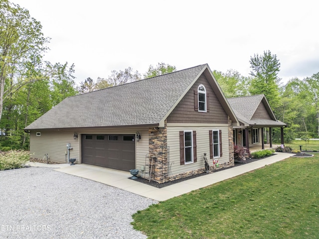 view of front of home with a shingled roof, stone siding, a garage, a front yard, and gravel driveway