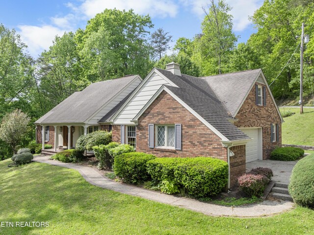 145 Lynn Ave, Jellico, TN 37762 - view of front of house featuring a front lawn, brick siding, a garage, a chimney, and covered porch