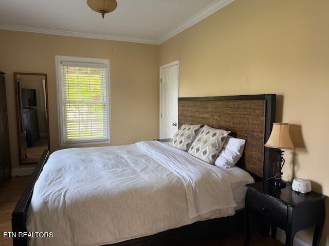 bedroom featuring crown molding, baseboards, and wood finished floors