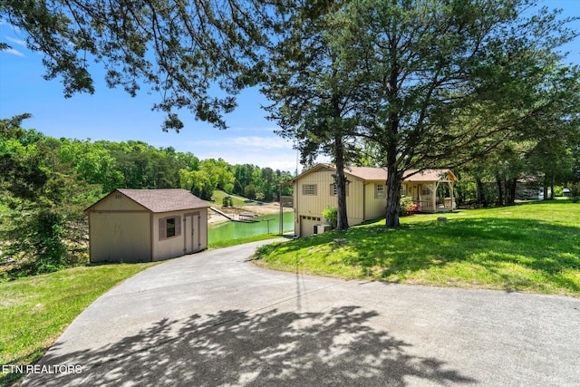 view of front of house with a garage, an outbuilding, driveway, and a front lawn
