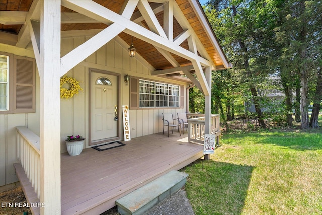 entrance to property featuring board and batten siding, a yard, and a deck