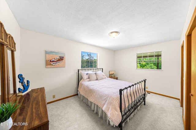 bedroom featuring baseboards, a textured ceiling, and light carpet