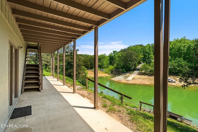 view of patio featuring visible vents, a water view, and stairway