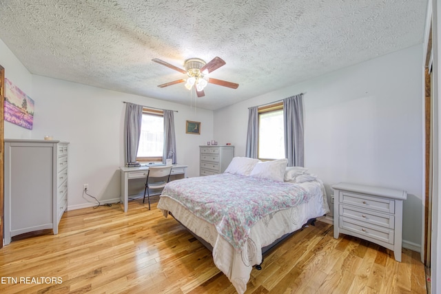 bedroom featuring a ceiling fan, a textured ceiling, baseboards, and light wood-style floors