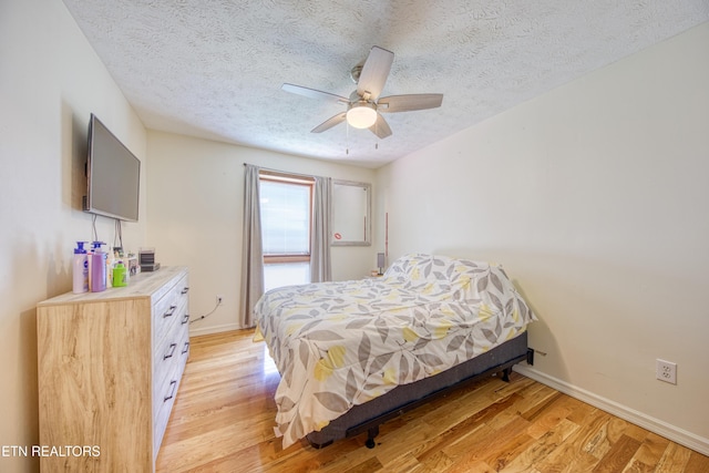 bedroom with baseboards, ceiling fan, light wood-type flooring, and a textured ceiling