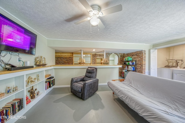 sitting room featuring ceiling fan, brick wall, finished concrete floors, a textured ceiling, and washer and dryer