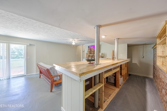 kitchen with a textured ceiling, butcher block countertops, baseboards, and finished concrete flooring