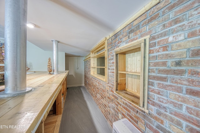 hall with brick wall and wood finished floors