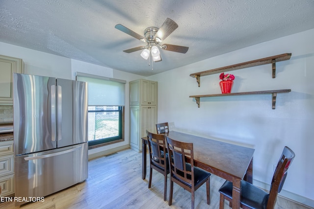 dining space with a ceiling fan, a textured ceiling, and light wood finished floors