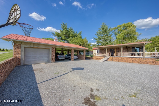 single story home with a garage, a chimney, brick siding, metal roof, and a carport