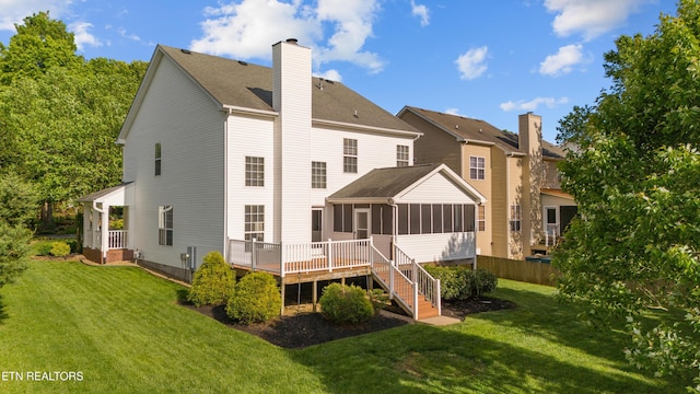 back of property featuring a lawn, a chimney, and a sunroom