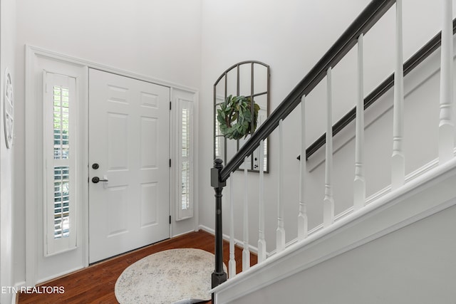 foyer entrance featuring a towering ceiling and dark wood-style floors