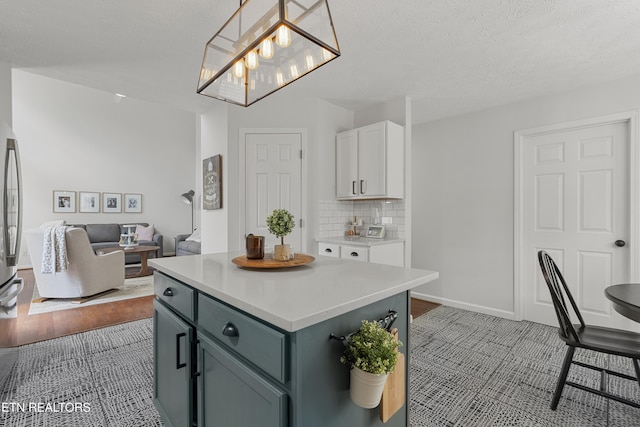 kitchen featuring light countertops, white cabinetry, open floor plan, tasteful backsplash, and a kitchen island