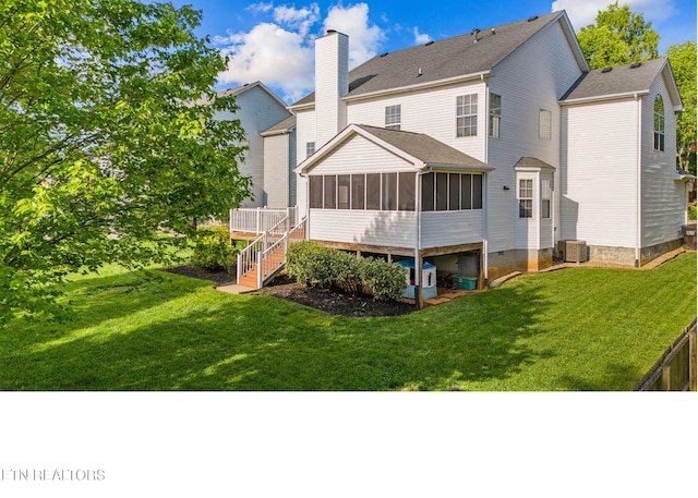 rear view of house with a yard, stairs, a chimney, and a sunroom
