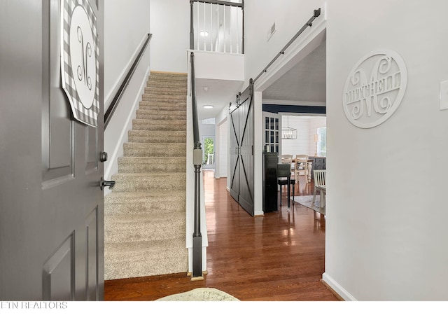 stairway featuring baseboards, a barn door, and wood finished floors