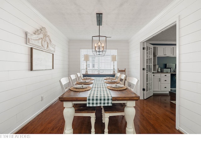 dining room with wooden walls, dark wood-style flooring, and ornamental molding