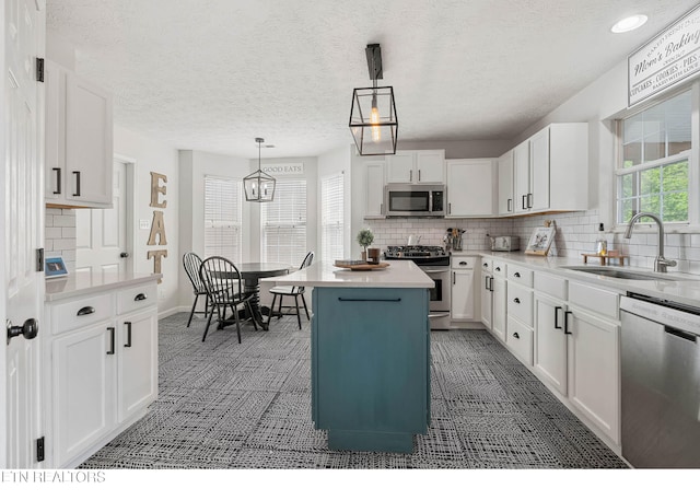 kitchen featuring light countertops, white cabinetry, tasteful backsplash, a sink, and appliances with stainless steel finishes