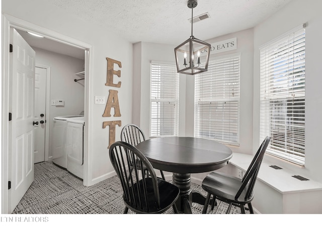 dining room featuring washer and dryer, a notable chandelier, a textured ceiling, baseboards, and visible vents