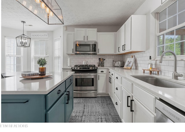 kitchen with an inviting chandelier, a sink, light countertops, a textured ceiling, and stainless steel appliances