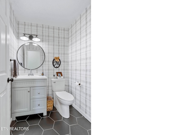 half bathroom featuring toilet, tile patterned flooring, and vanity